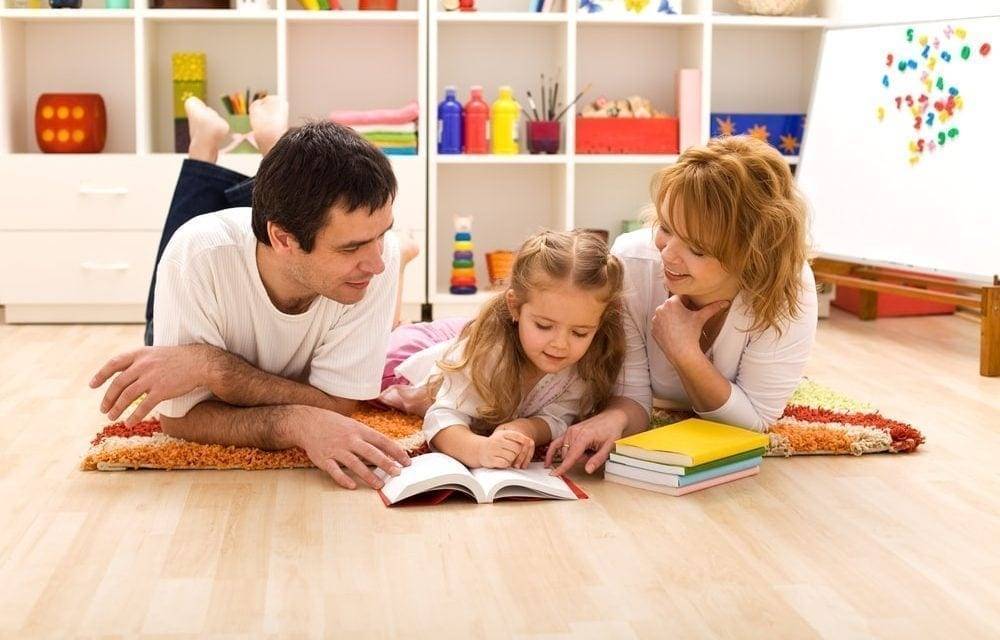 dad-mom-and-daughter-lying-on-the-ground-reading-together