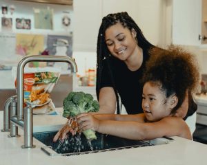 mom-teaching-daughter-to-wash-vegetables-by-tyson-at-unsplash